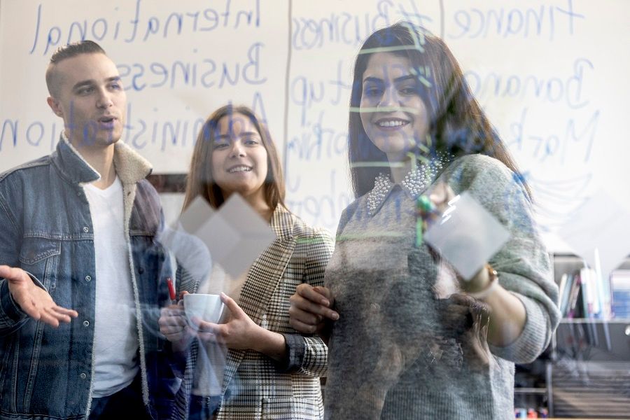 Studierende arbeiten im Team, schreiben auf das Glas, machen ein Brainstorming, machen Notizen